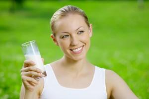 Girl with a bottle of kefir on a background of green grass