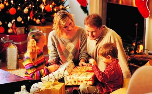 Children unpack gifts near the Christmas tree with parents