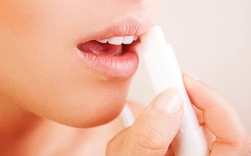 Girl smears her lips with hygienic lipstick