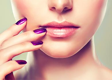 Holds a hand in the corners of the lips