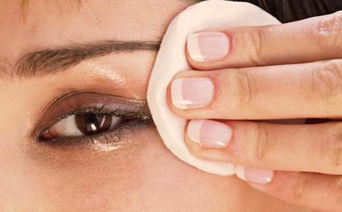 Brown-eyed beauty wipes her eyes with a cotton pad