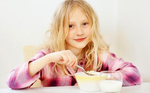 Girl with an angelic face eats porridge with pleasure