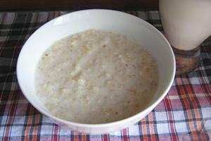 Milk porridge in a white plate and on a checkered tablecloth