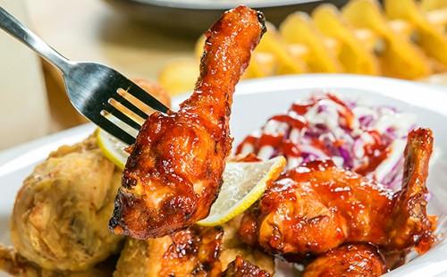 A fork sticks in fried chicken in a sauce