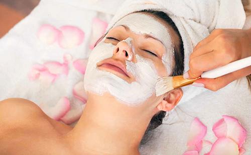 White mixture on a woman's face and scattered pink petals