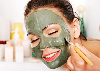 Girl puts a clay mask on her face