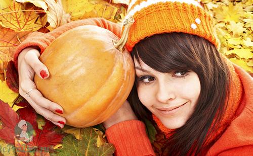Girl in an orange cap hugs the fruits of autumn