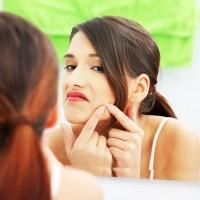 The girl in front of the mirror violently crushes a pimple