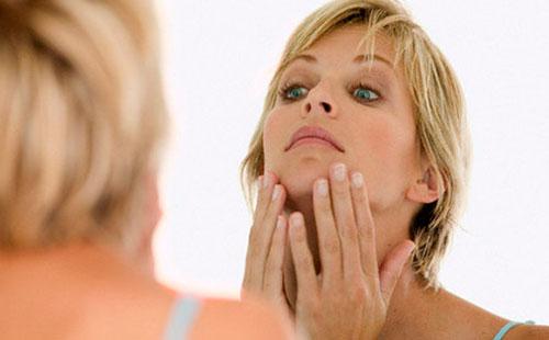 Woman examines her face.