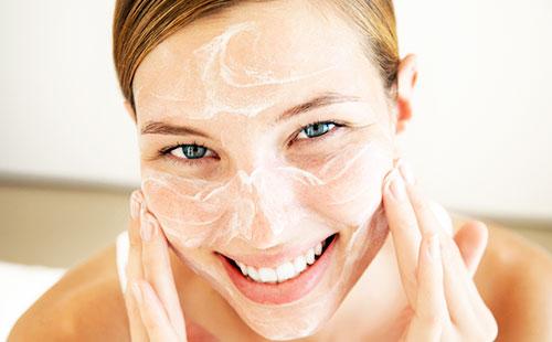 Girl applies a scrub on her face