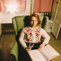 Lisa in a green chair and with a glass of wine