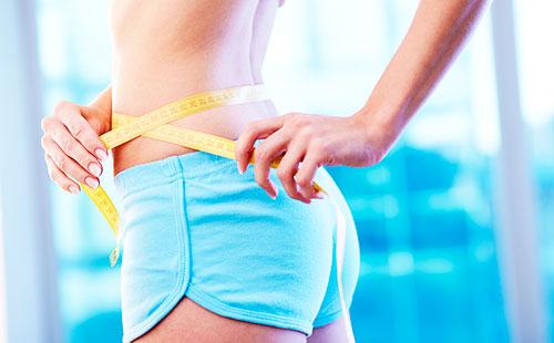 The girl in shorts measures a waist