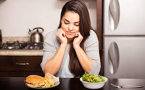 Dark-haired girl looks at a hamburger