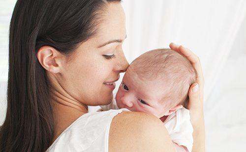Mom holds a newborn with a smile