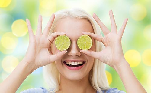 The girl holds two circles of lemons