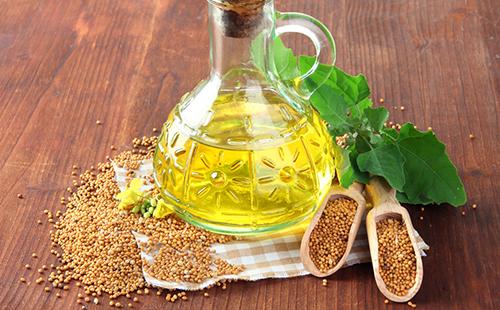Glass jug with mustard oil and sprinkled seeds
