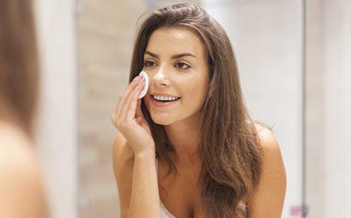 Dark-haired girl erases makeup with a cotton pad
