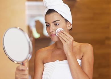 Woman looks in the mirror and rubs her face