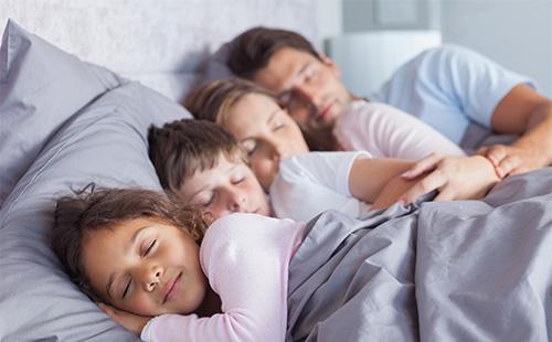 Family sleeping on bed