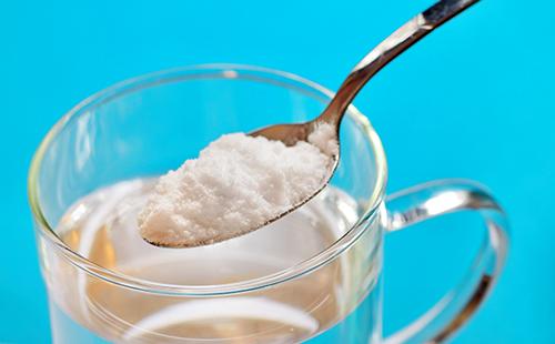 A spoon of soda over a glass of water