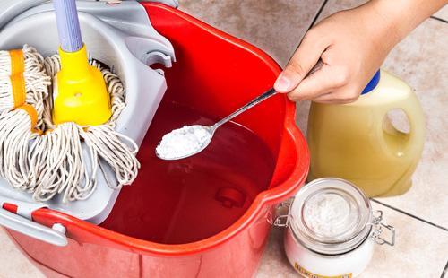 Soda in a spoon and a bucket of water