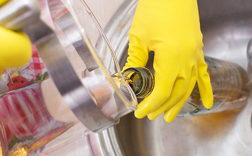Hand in yellow glove pours caustic liquid