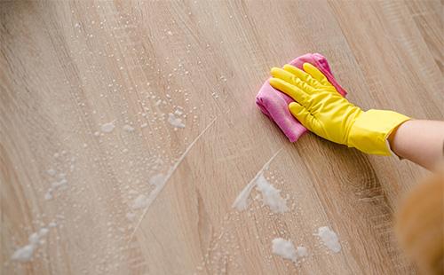 A gloved hand is washing a laminate with a rag