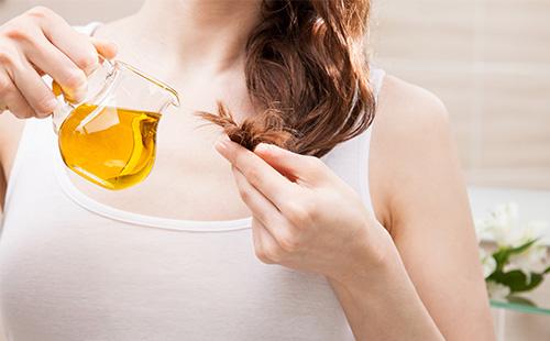 Woman pours oil on her hair