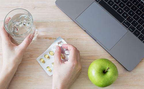 Glass with water and pills in hands.