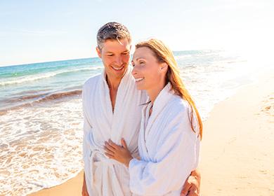 Happy couple in bathrobes by the sea