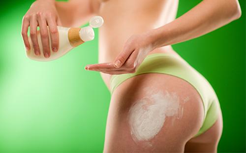 Girl smears hips with cosmetic