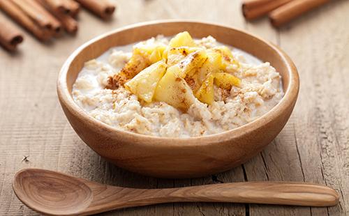 Oatmeal with baked apples in a wooden bowl