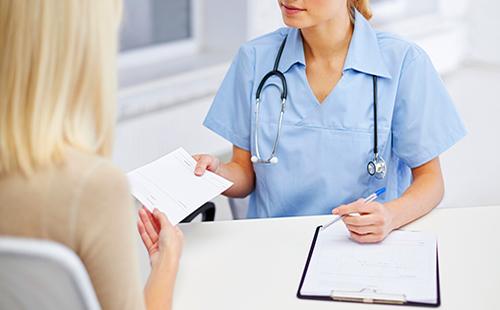 The doctor gives a woman a prescription on a piece of paper