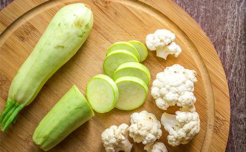 Sliced zucchini and cauliflower on a wooden board