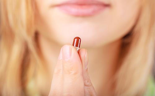 Girl holds a pill in her hand
