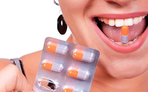 Girl with a smile holds a capsule in her teeth