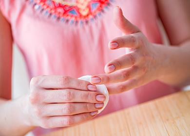 Girl wipes her nails with a cotton pad