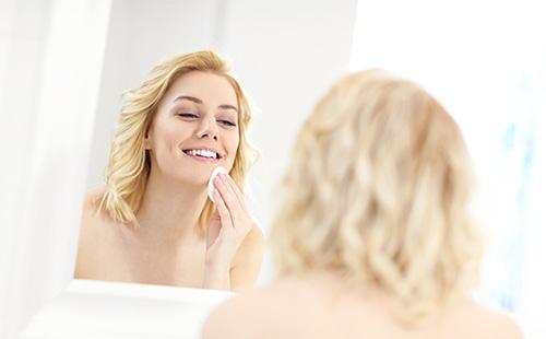 Woman wipes her face with a cotton pad