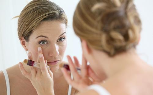 Woman smears face with foundation