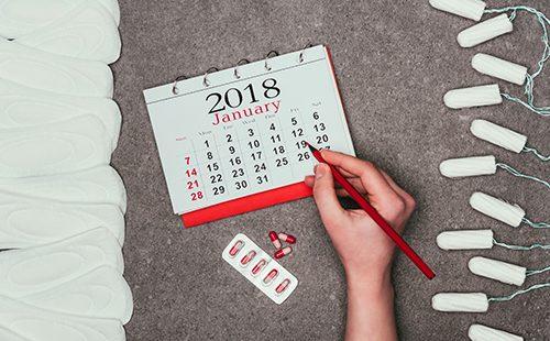 Woman overlaid with hygiene products and writes on the calendar