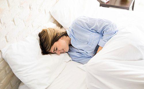 Young woman suffers in bed