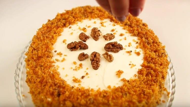 Having greased the top and sides of the cake with cream, sprinkle the sides with crumbs, decorate the dessert with nuts.