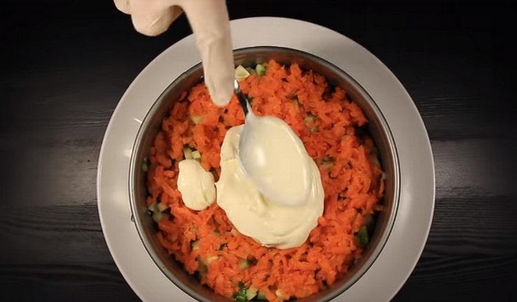 On top of the cucumber, lay out a layer of grated carrots and grease it with mayonnaise.