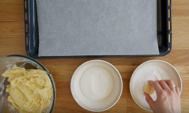 First, roll the ball in sugar, and then in icing sugar.