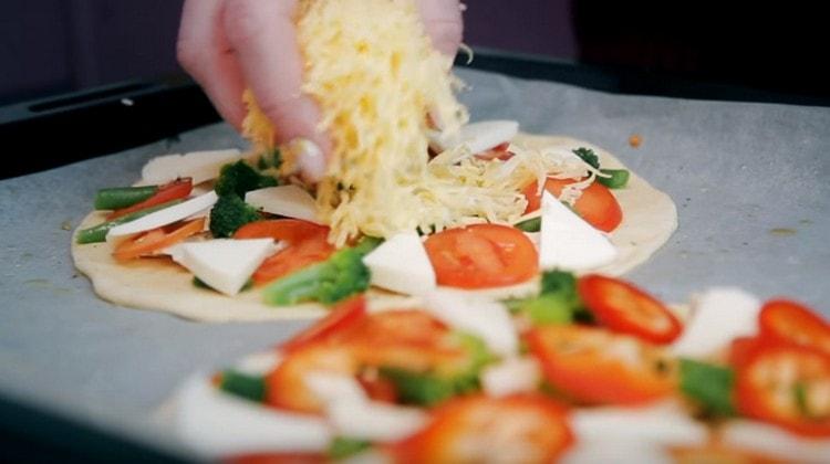 Sprinkle pizza with grated cheese and put in the oven.