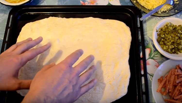 On a greased baking sheet, spread half the prepared dough.