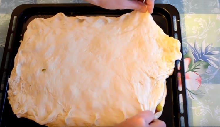 Cover the filling of the second half of the dough, pinch the edges.