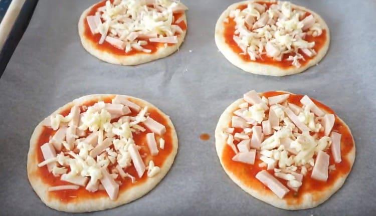 Spread ham and cheese on each mini pizza.