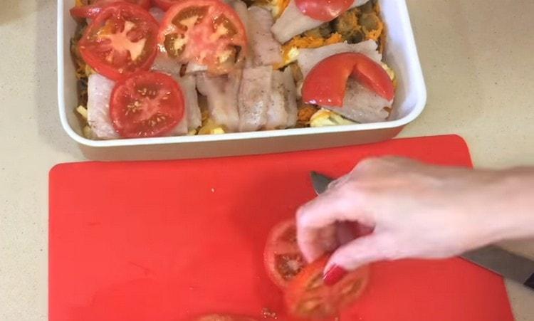 In the baking dish we add vegetables, fish, cover it with slices of tomato.
