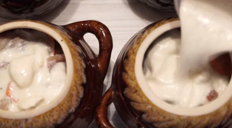 Pour the components in pots with sour cream sauce.